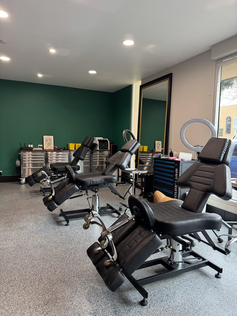 Mother Goose tattoo studio with professional chairs, green feature wall, and ring lights