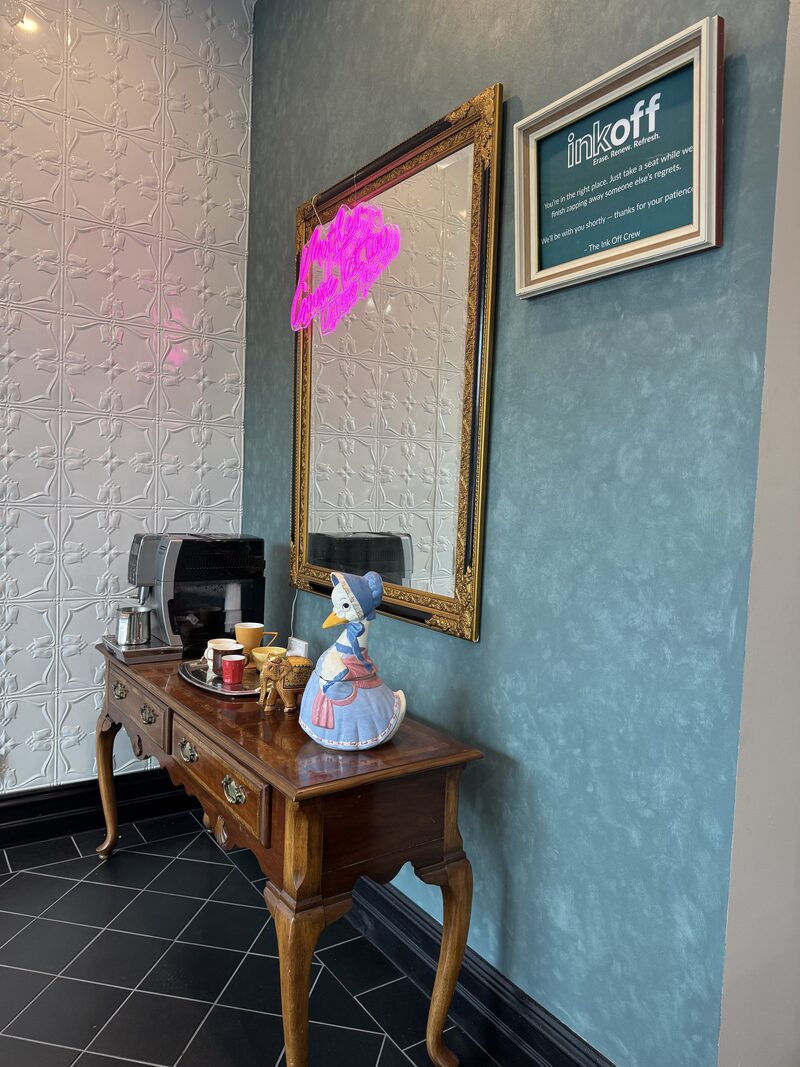 Ink Off waiting area with espresso bar, gold baroque mirror, and Venetian plaster walls